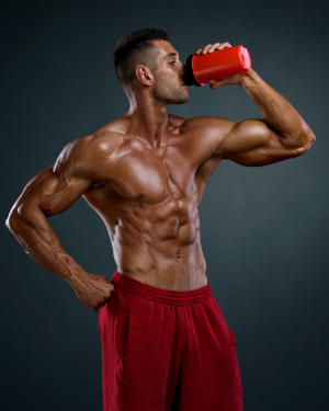 Muscular man in red shorts drinking a protein shake after workout